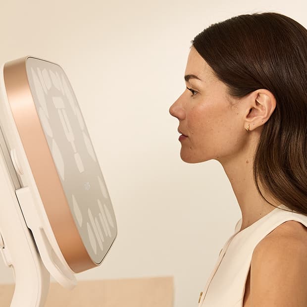 Side profile of woman facing the Aura 3D imaging device during a consultation
